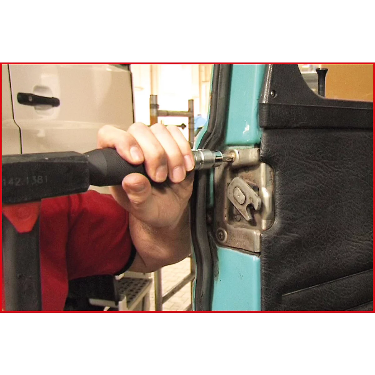 Eine Person verschraubt mit einem Schraubenzieher ein Türscharnier.